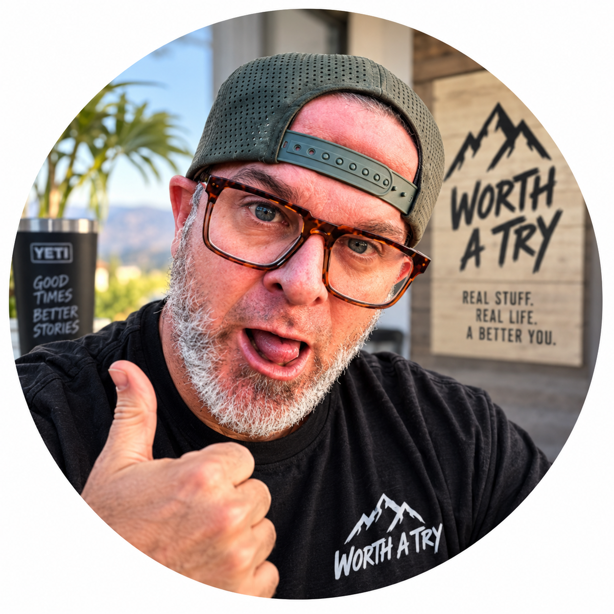 Elliot Parker wearing a backward green hat and glasses, giving a thumbs-up